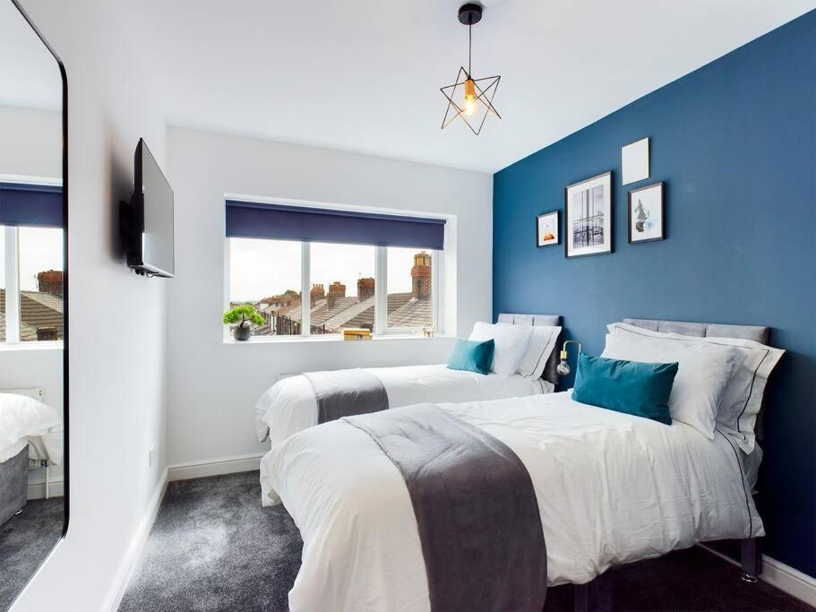 Luxurious 3 bedroom Flat في ليفربول: سريرين في غرفة باللون الأزرق والأبيض