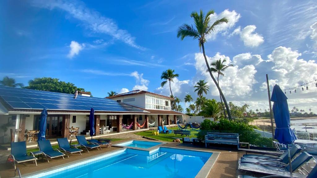 a house with a swimming pool and palm trees at Pousada a Capela in Arembepe