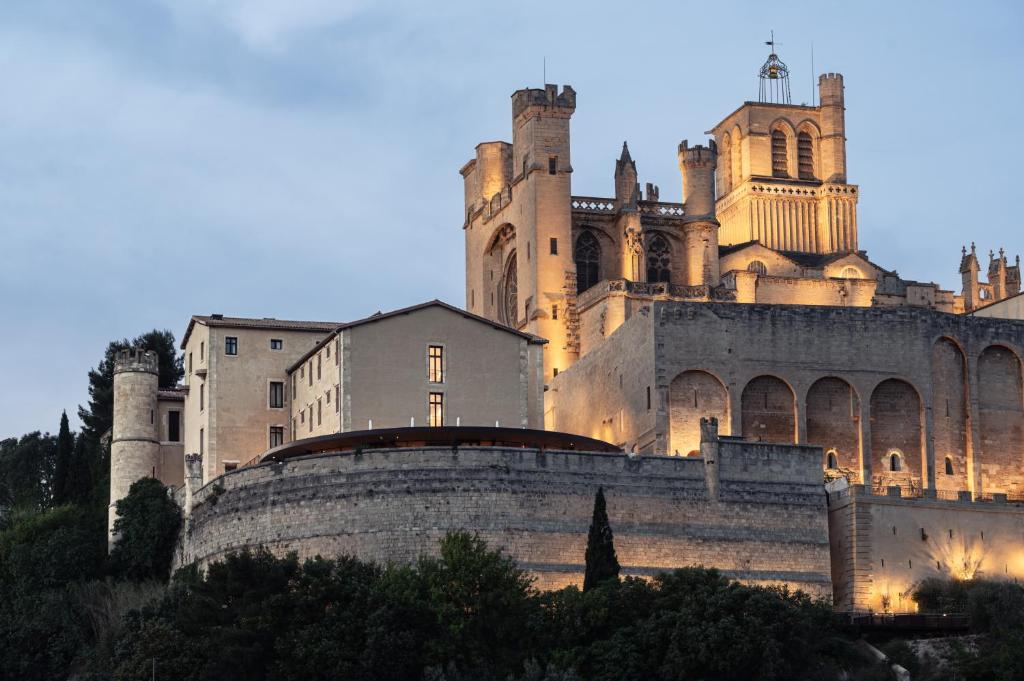 a castle is lit up at dusk at Hôtel La Prison in Béziers