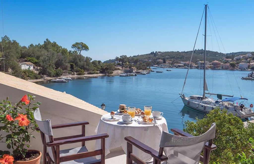 a table on a balcony overlooking a river with a boat at The Harbour House in Gaios