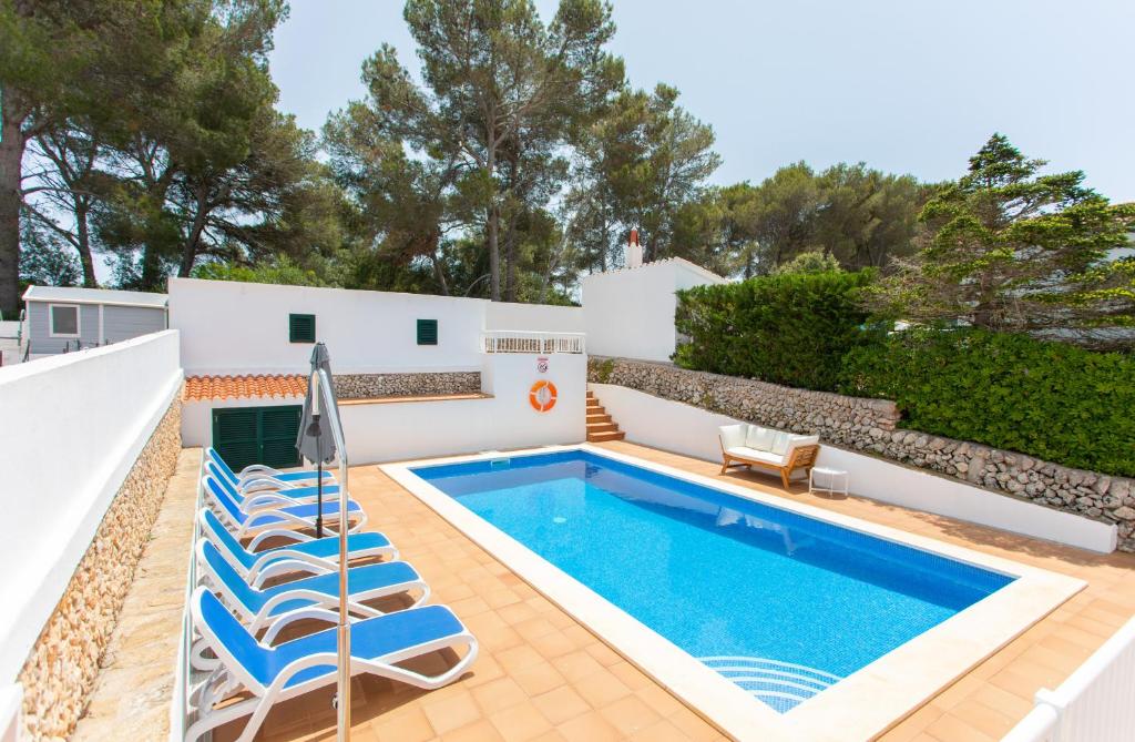 uma villa com uma piscina e espreguiçadeiras em Villa Xaloc em Cala Galdana