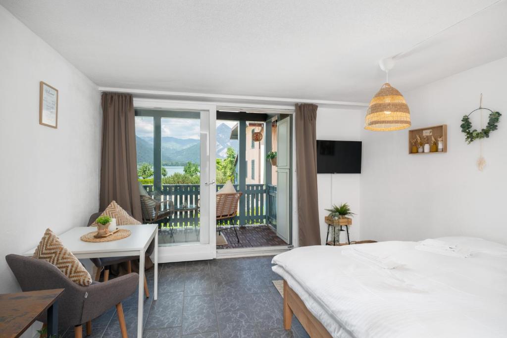 Schlafzimmer mit einem Bett und einem Tisch sowie einem Balkon in der Unterkunft "Boho Oase" with lake view and pool in Därligen