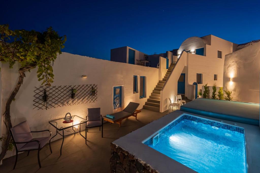 a villa with a swimming pool at night at Santorita Suites in Akrotiri