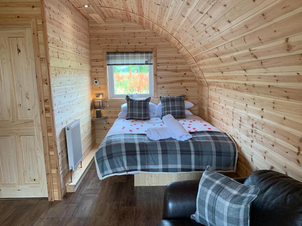 una camera con un letto in una cabina di legno di Pond View Pod 3 With Private Hot Tub - Pet Friendly -Fife - Loch Leven - Lomond Hills a Kelty