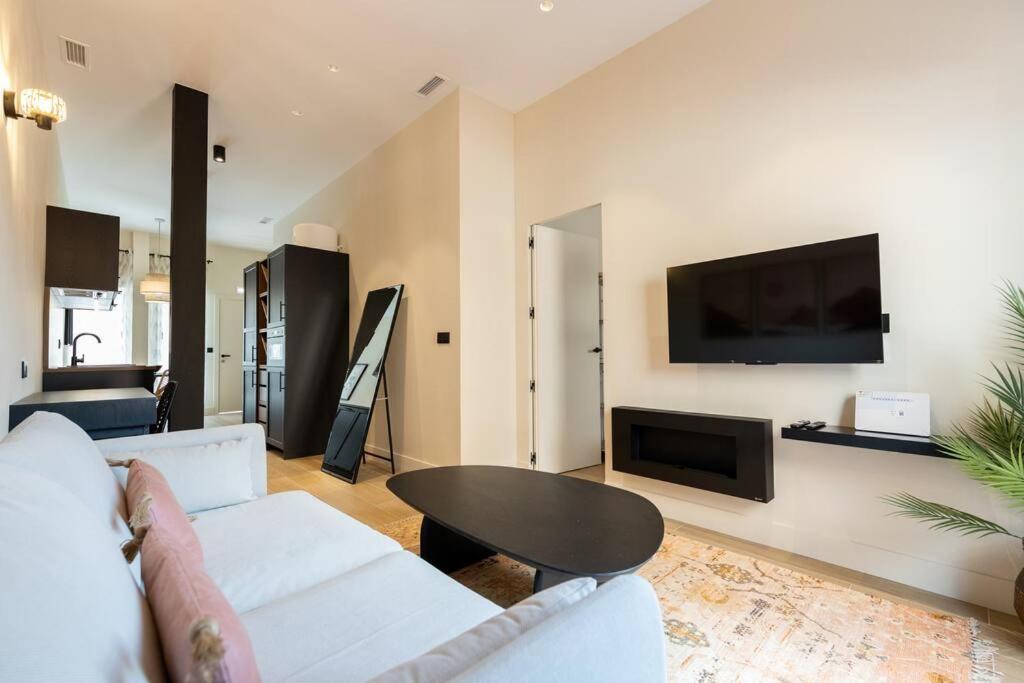 uma sala de estar com um sofá, uma mesa e uma televisão em Amplio y cómodo apartamento cerca Plaza Castilla em Madri