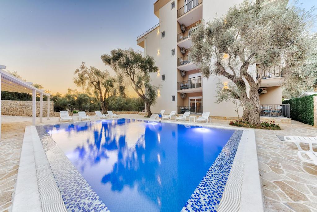 a swimming pool in front of a building at Akhdar Apartments in Utjeha