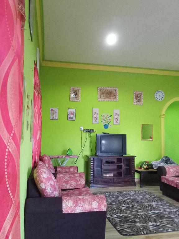 uma sala de estar com um sofá e uma televisão em ROSMA HOMESTAY em Kampong Ru Sepuloh