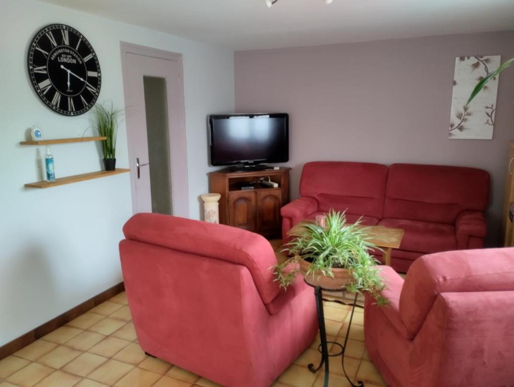 a living room with two red chairs and a tv at Chez David et Sonia in Éguzon-Chantôme