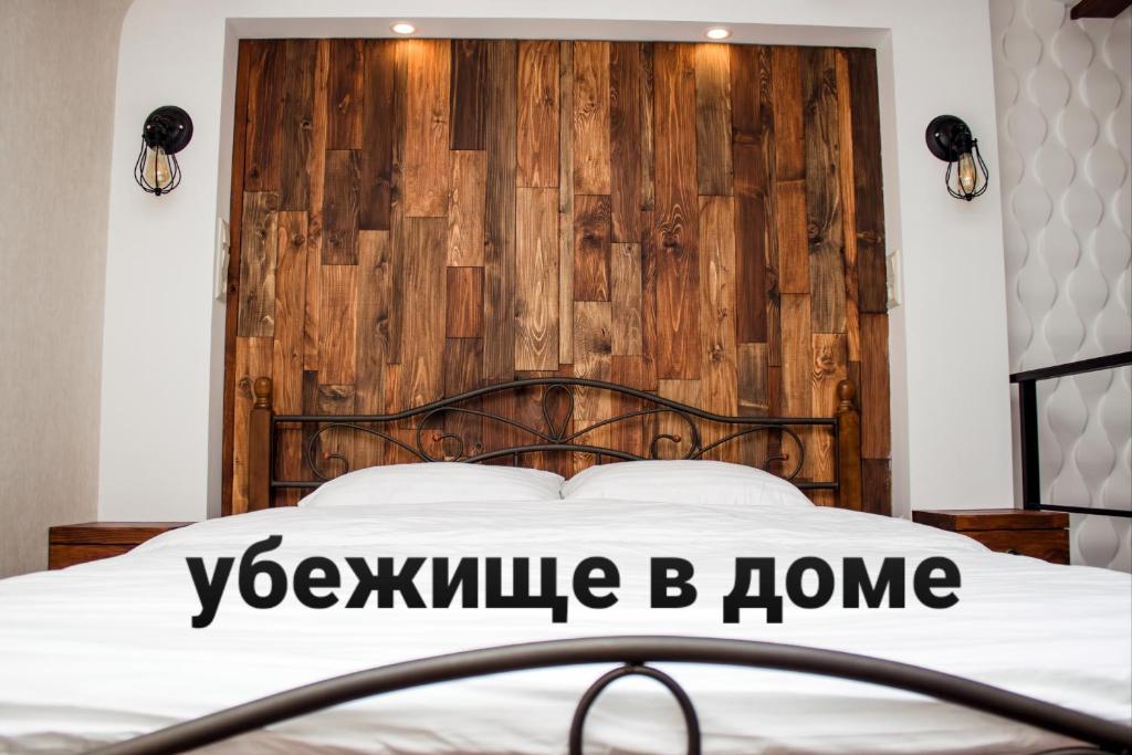 a bedroom with a bed with a wooden headboard at Apartment in the city center in the house with Atlantes in Odesa
