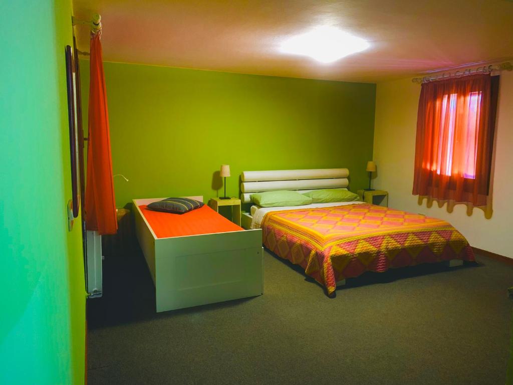 een groene kamer met 2 bedden en een tafel bij B&B Casa Linda in Pradipozzo