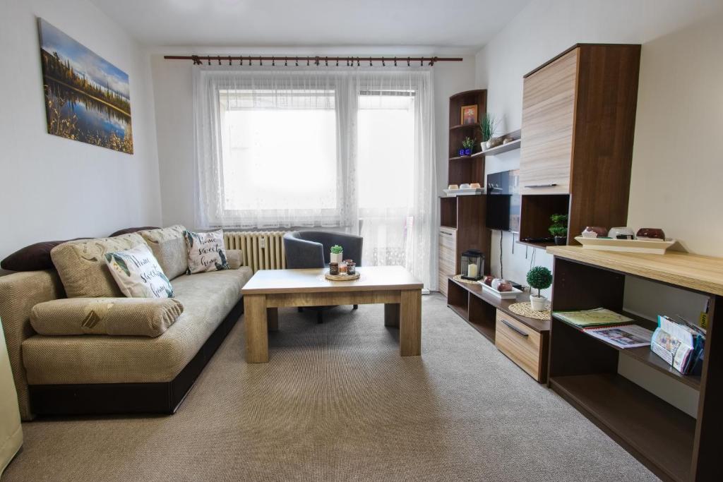 ein Wohnzimmer mit einem Sofa und einem Tisch in der Unterkunft Apartmán u Klínovce in Kovářská