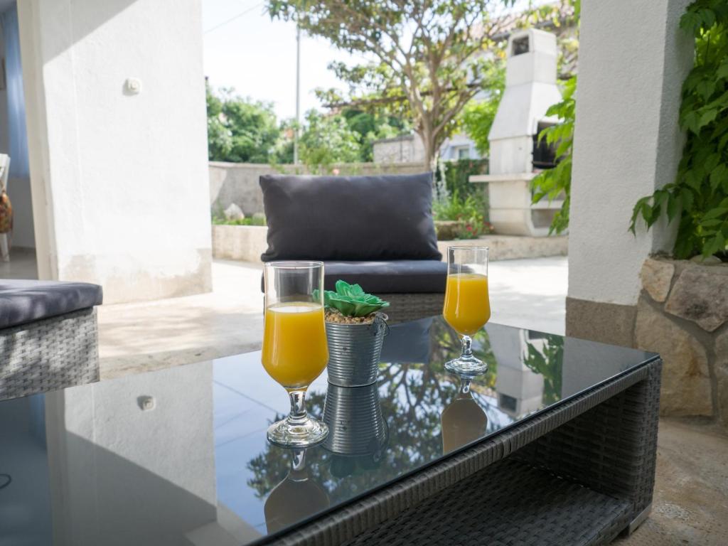 two glasses of orange juice on a glass table at Holiday Home Vera in Malinska