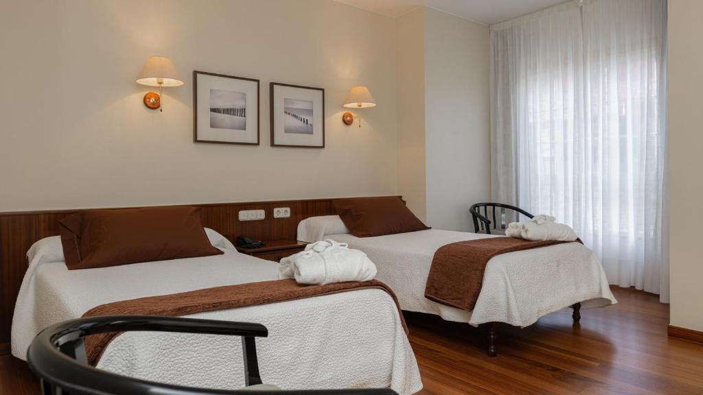 a hotel room with two beds with towels on them at Balneario de Carballo in Carballo