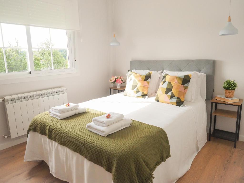 a bedroom with a large white bed with towels on it at Casa Rural Horta De Arriba in Porta
