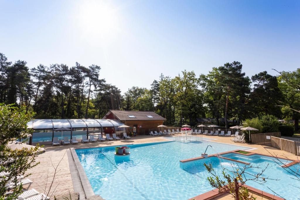 une grande piscine avec un bâtiment en arrière-plan dans l'établissement Camping La Pinède, à Excenevex