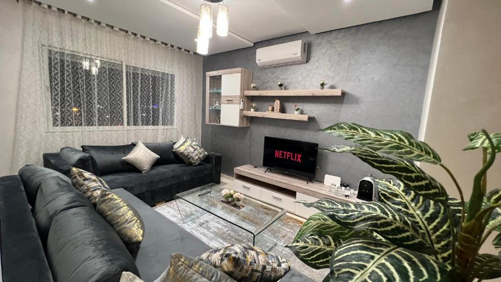 ein Wohnzimmer mit einem schwarzen Sofa und einem TV in der Unterkunft Haut Standing Appartement - Centre Ville Oujda in Oujda