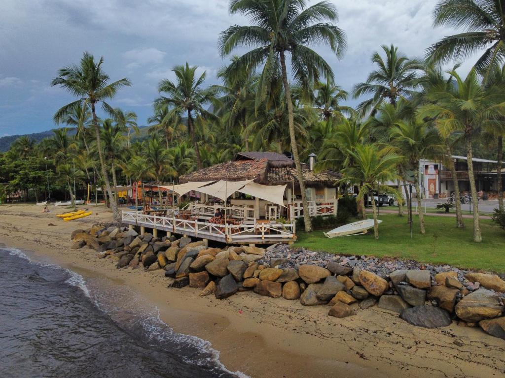 a resort on the beach with palm trees at Chalé Ilhabela Apartamento Ilhabela Bangalô Ilhabela Bangô Brasil in Ilhabela