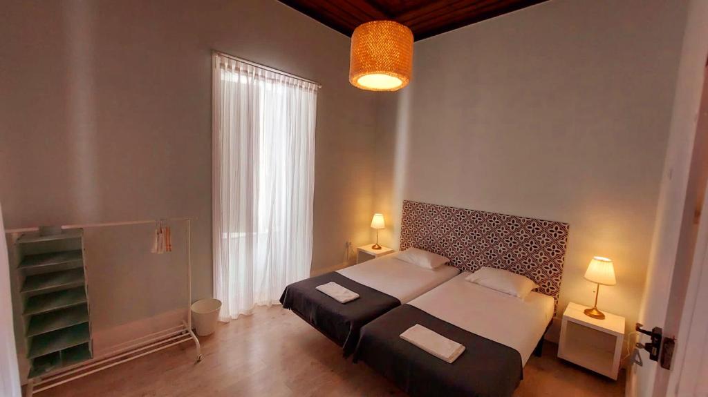 a bedroom with a large bed and a large window at Hostel A Casa da Árvore in Faro