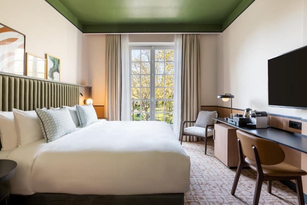 ein Hotelzimmer mit einem großen Bett und einem Schreibtisch in der Unterkunft Le Parchamp, a Tribute Portfolio Hotel, Paris Boulogne in Boulogne-Billancourt