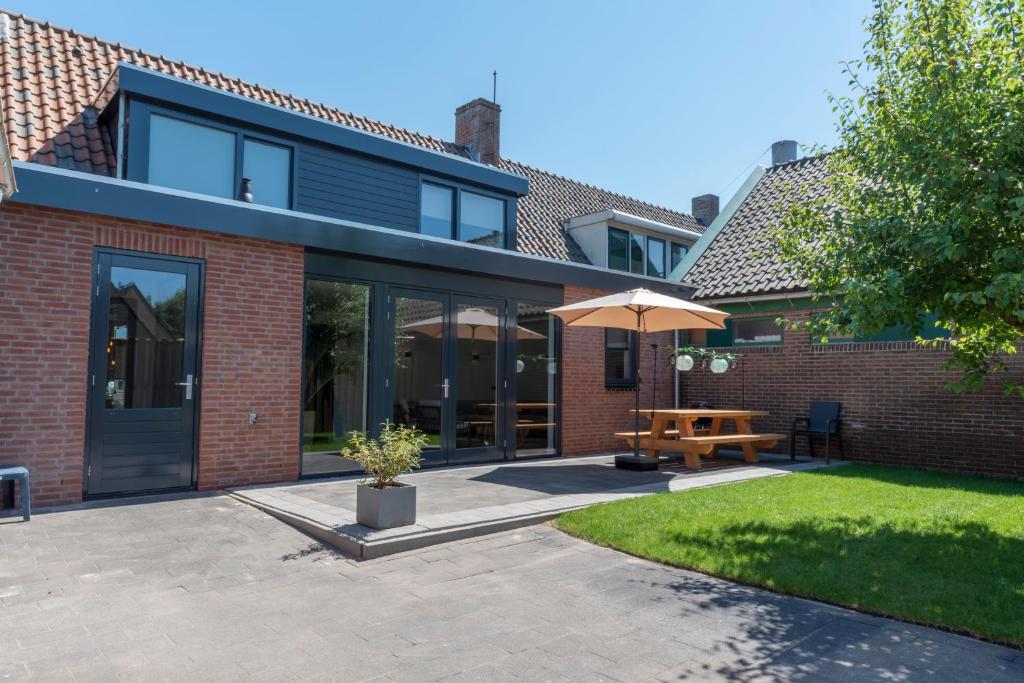 ein Backsteinhaus mit einer Terrasse und einem Sonnenschirm in der Unterkunft De Zuivelhandel in Petten