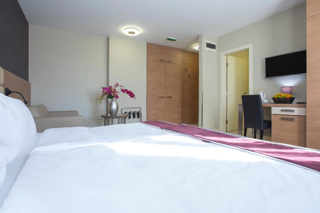 a large white bed in a room with a desk at Hotel Srbija Garden-FREE PARKING in Belgrade