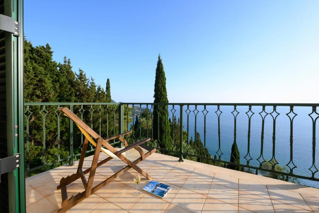 a wooden bench on a balcony overlooking the water at Nisos Sunset Apartments Agios Gordios in Corfu