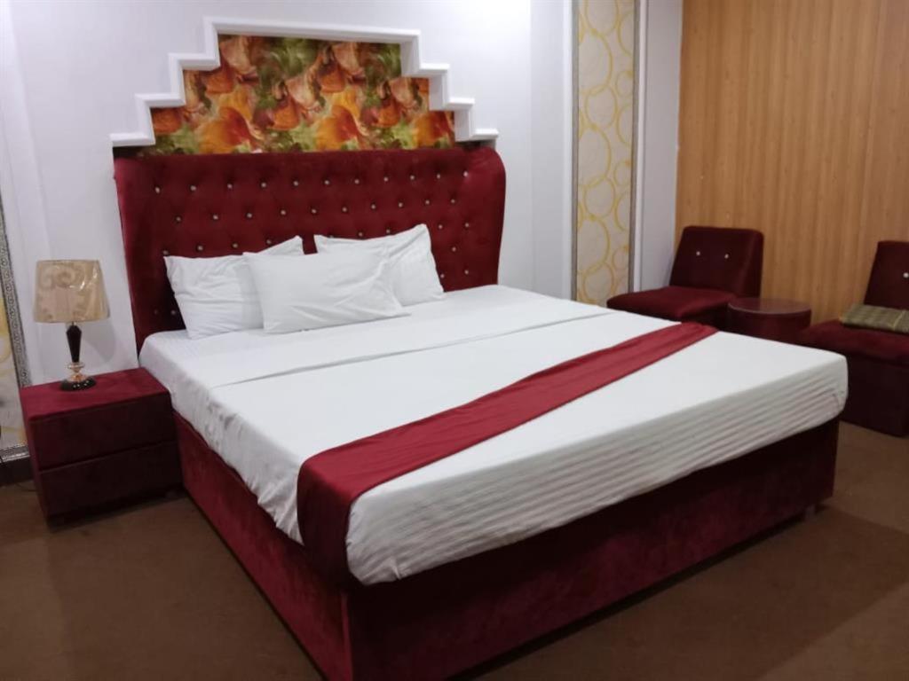 a bedroom with a large bed with a red headboard at Helen One Hotel in Lahore