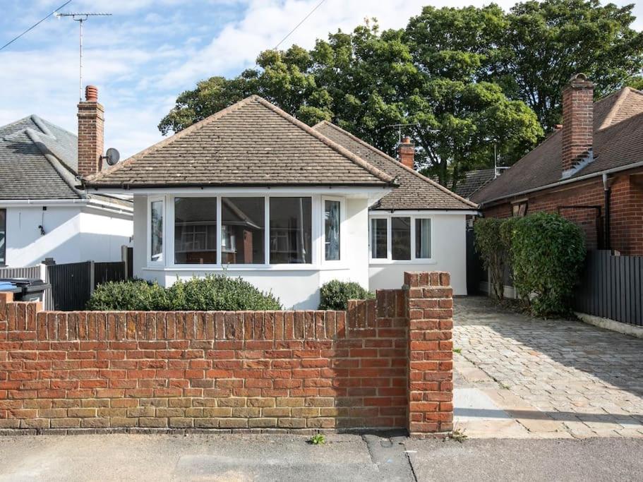 una cerca de ladrillo frente a una casa blanca en Seaside Family Bungalow for 5 people with garden and driveway parking, en Kent