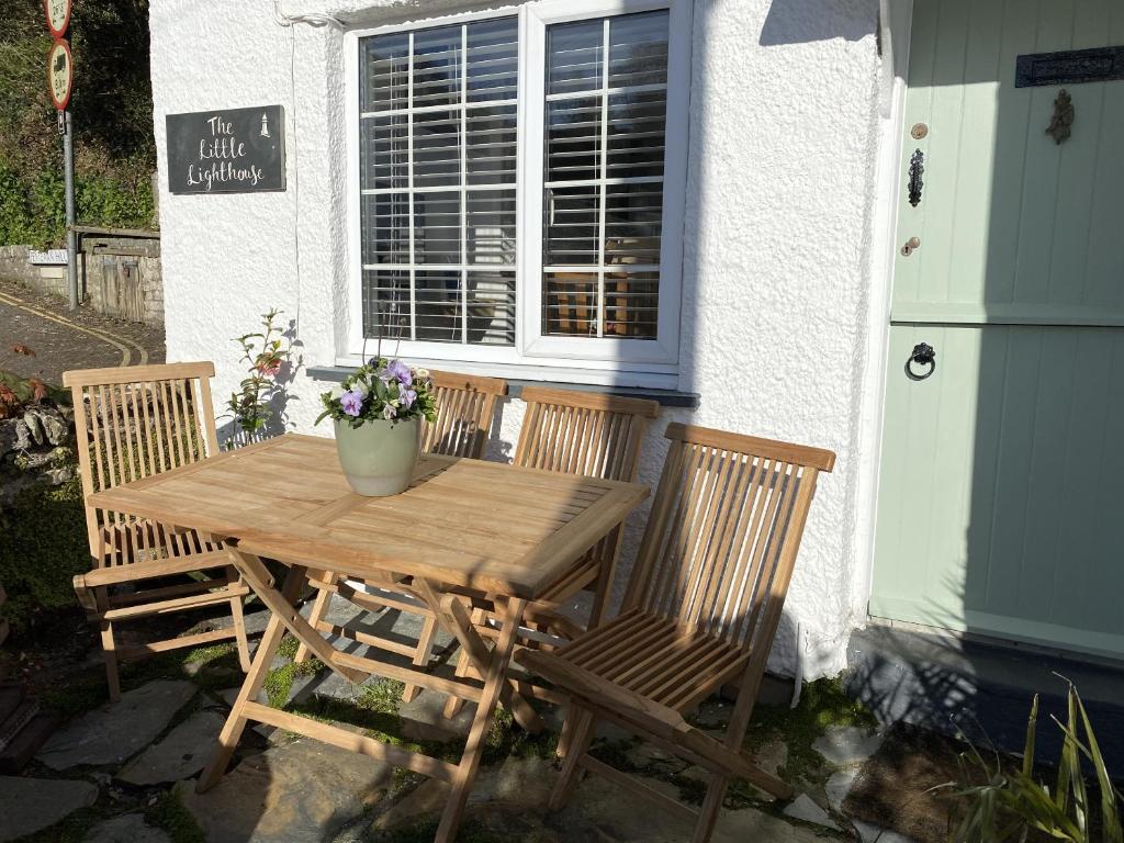 a wooden table and chairs outside of a building at The Little Lighthouse - 2 minutes from the beach in Pentewan