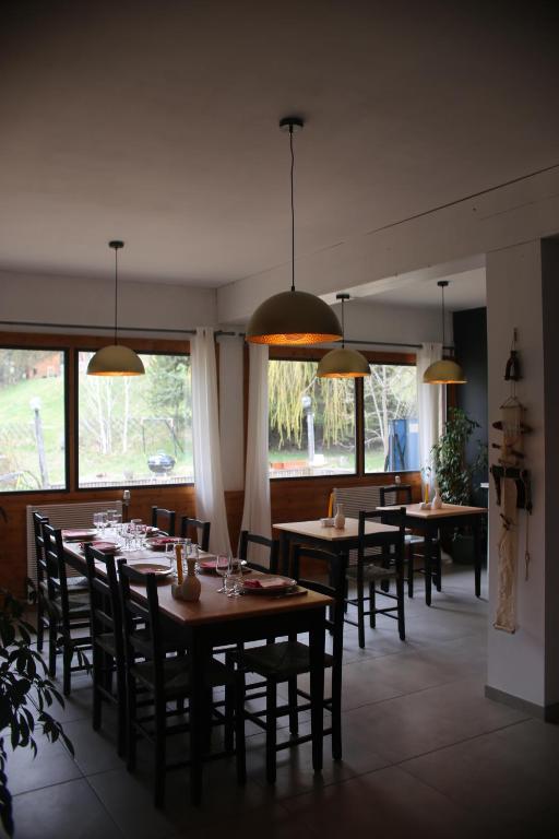 une salle à manger avec tables, chaises et fenêtres dans l'établissement Maison L'Aiguille - 2 appartements, 5 chambres et table d'hôtes au pied de la montagne à la station de Laye, à Laye
