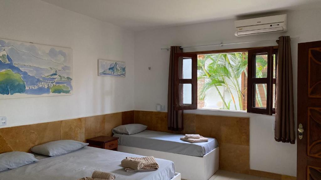 um quarto com duas camas e uma janela em Pousada Wind Paracuru em Paracuru