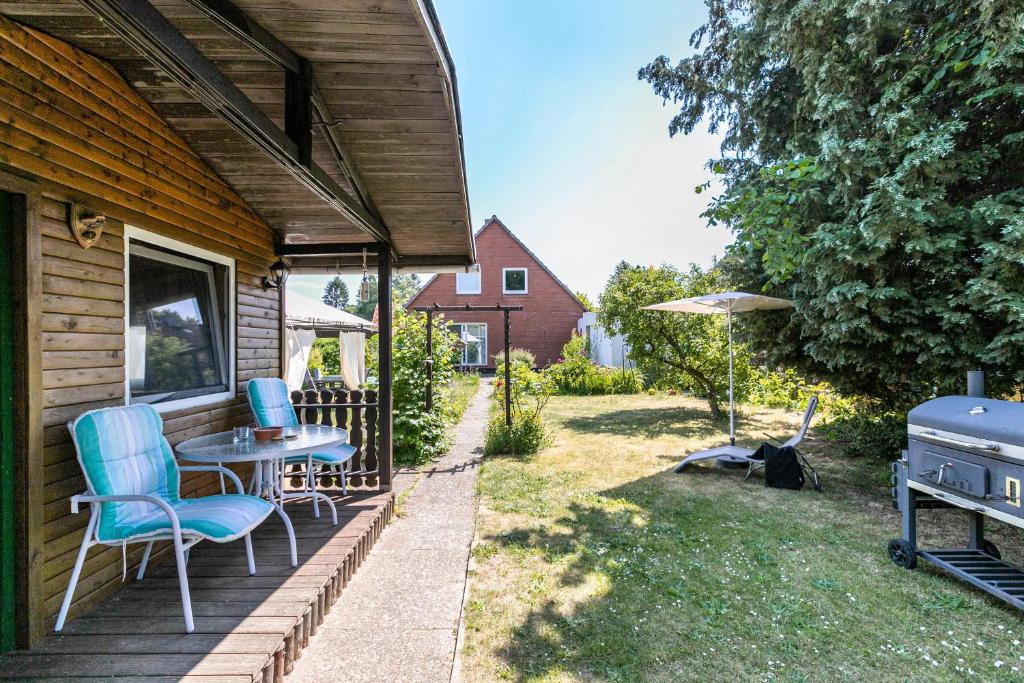 eine Terrasse mit einem Tisch, Stühlen und einem Grill in der Unterkunft Garden House in Kiel