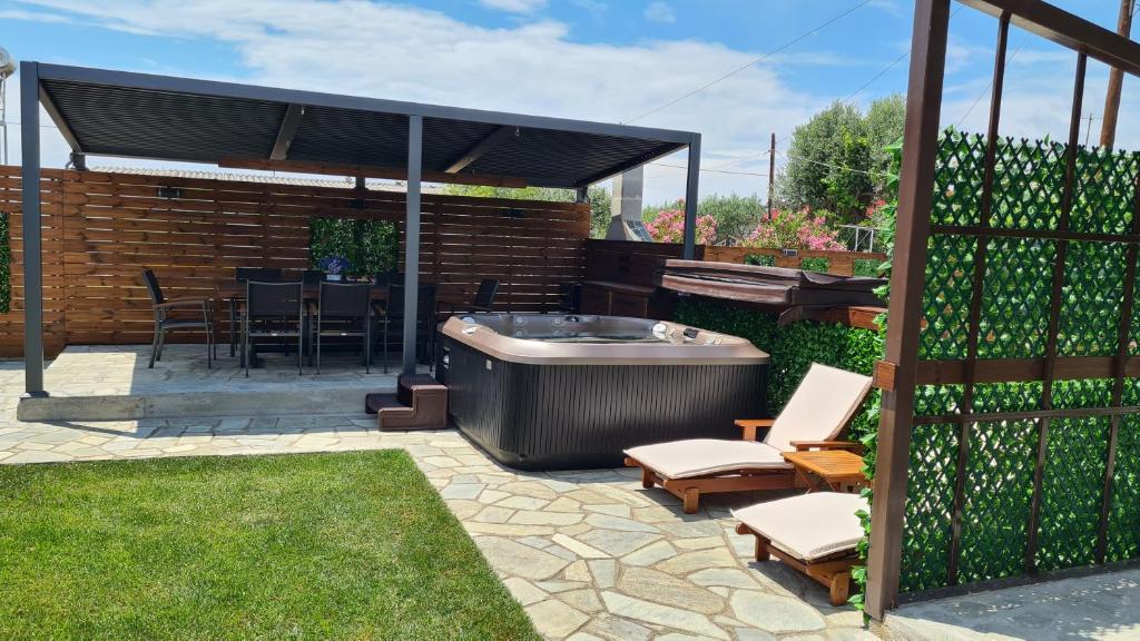 un patio trasero con bañera de hidromasaje, mesa y sillas en OASIS BEACH HOUSE en Vergia