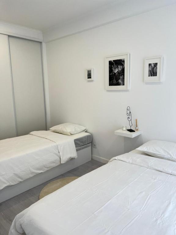 2 camas en una habitación con paredes blancas en Neptun guest house en Queluz