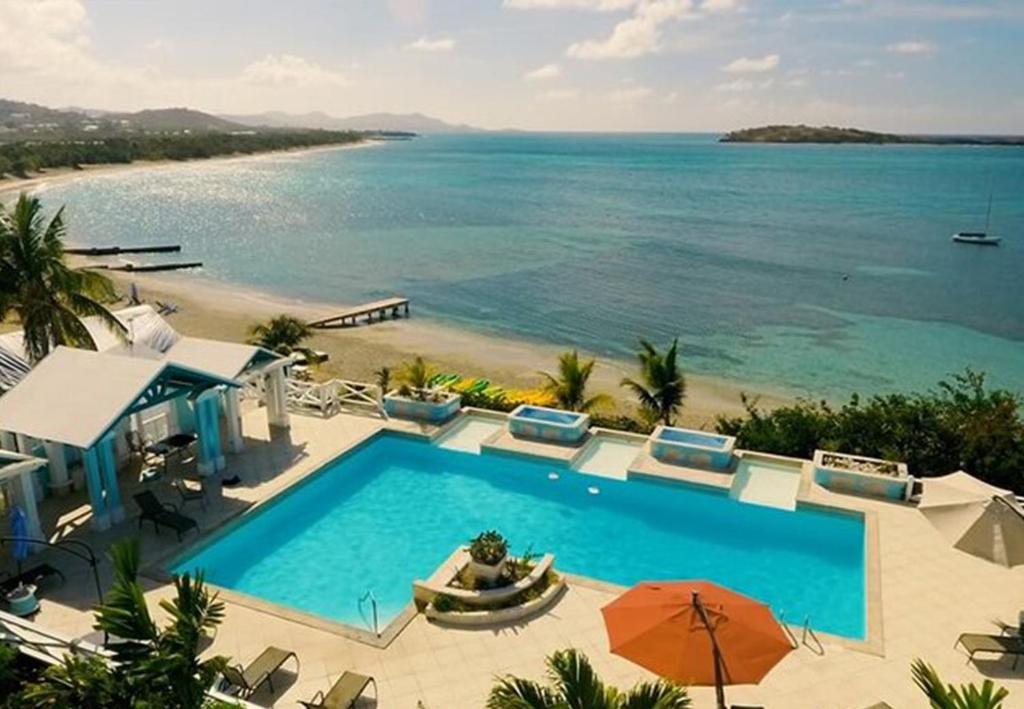 una piscina junto a una playa con el océano en Bungalows On The Bay en Christiansted