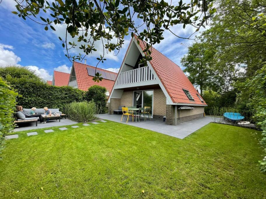 a house with a red roof and a yard at Vakantiewoning Sneekermeer, huur sloep of zeilboot mogelijk in Goingarijp