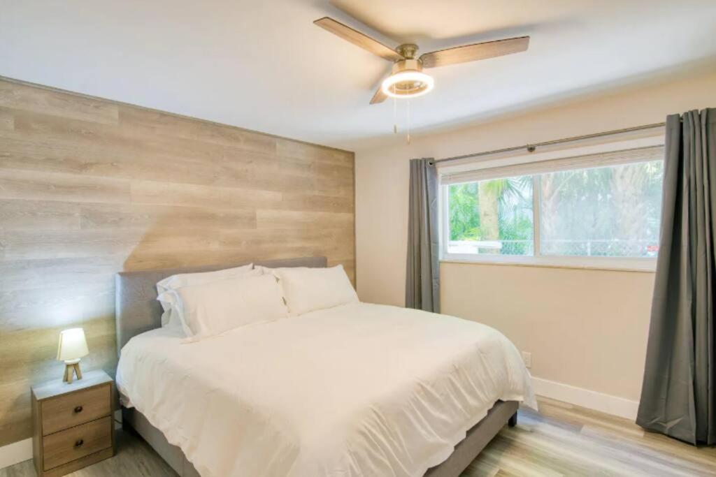 a bedroom with a bed with a ceiling fan and a window at Dog friendly condo with beach access, hot tub, firepit in West Palm Beach