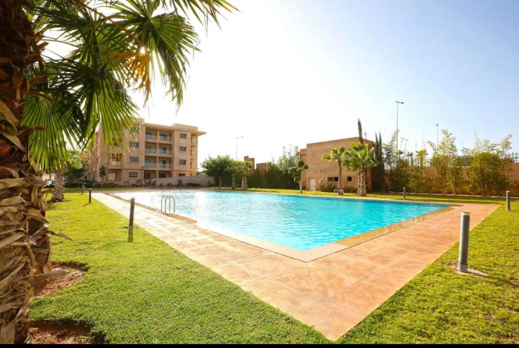 een groot zwembad in een park met een palmboom bij Résidence Coralia les orangers in Marrakesh