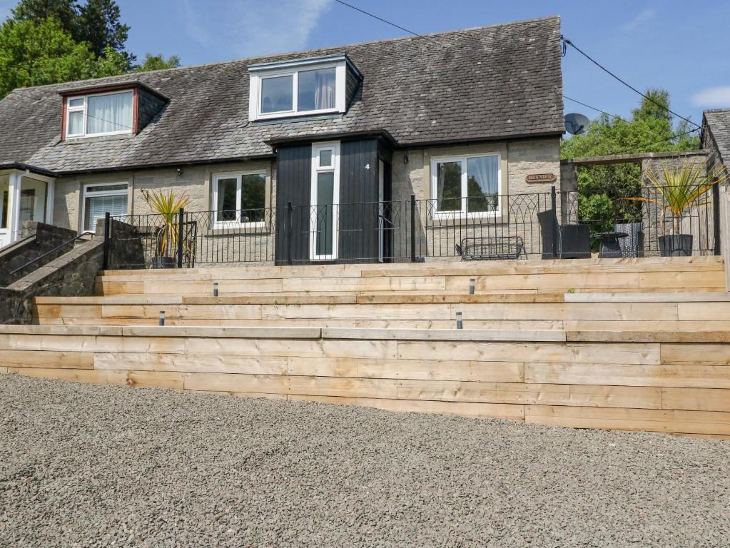 a house with a wooden retaining wall and stairs at Ben View in Arrochar