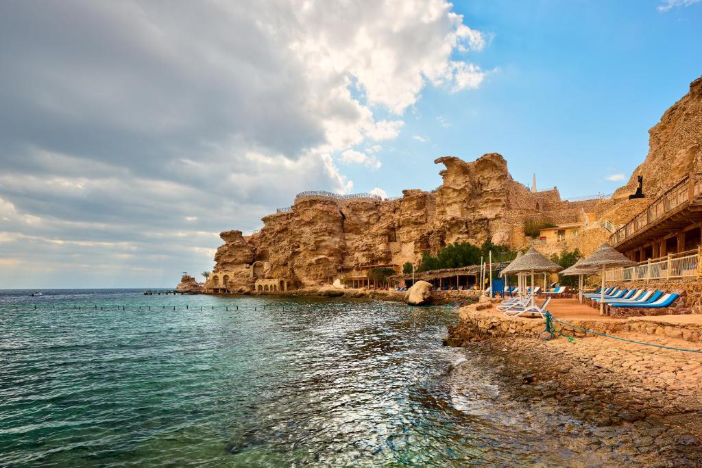 a beach with chairs and the water in front of a mountain at Dreams Vacation Resort - Sharm El Sheikh in Sharm El Sheikh