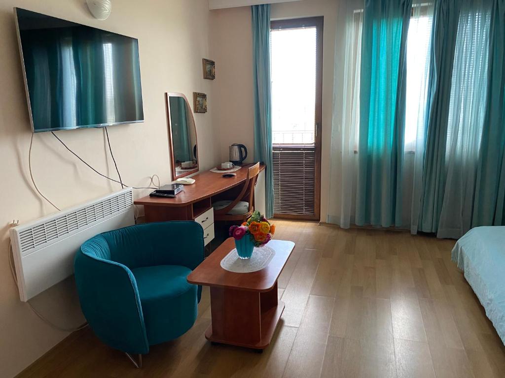 a room with a bed and a desk and a blue chair at Guest House Golden Flake 4km from Bolata beach in Bŭlgarevo