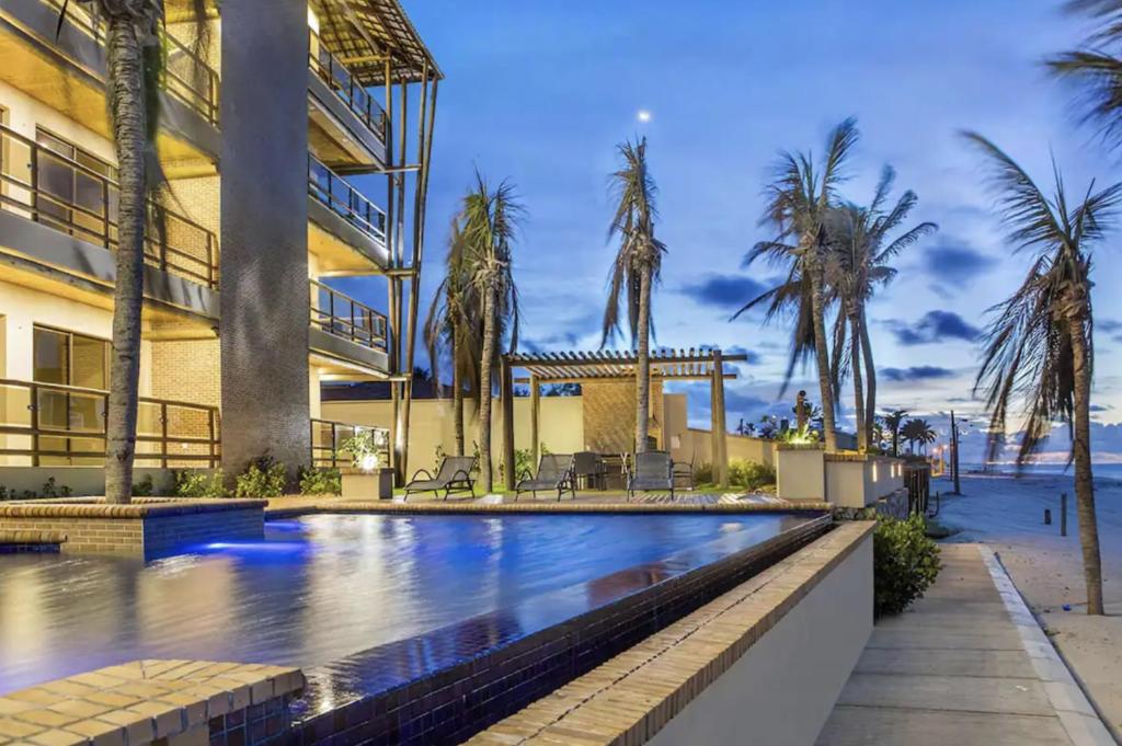 a building with a swimming pool next to the beach at Beach front Varandas Do Mar in Cumbuco