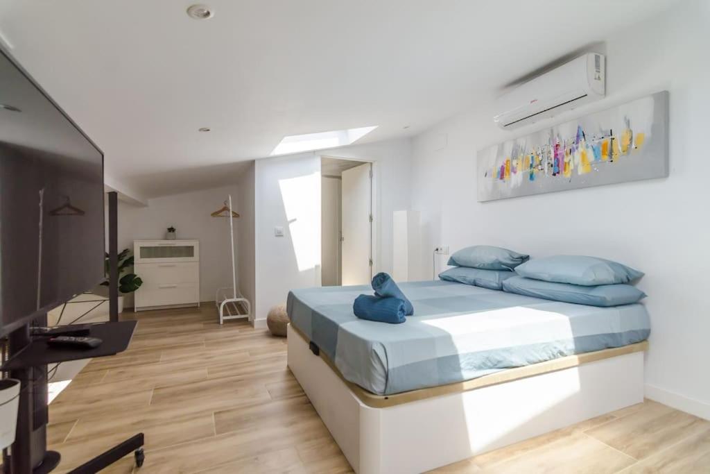 1 dormitorio con 1 cama con almohadas azules y TV en Luxury apartament Lloret, en Lloret de Mar