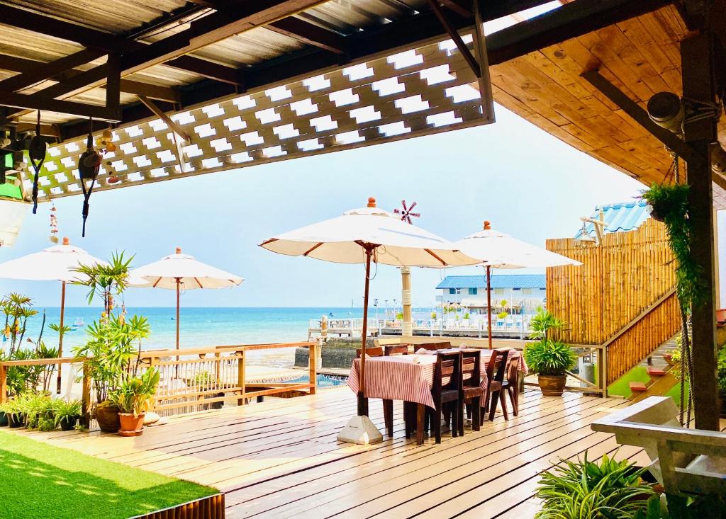 - une terrasse en bois avec une table et des parasols sur la plage dans l'établissement BaanRabiangnam kohlarn, à Ko Larn