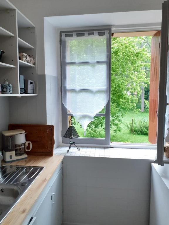 uma cozinha com uma janela com vista para um quintal em Les chênes blancs em Aubin