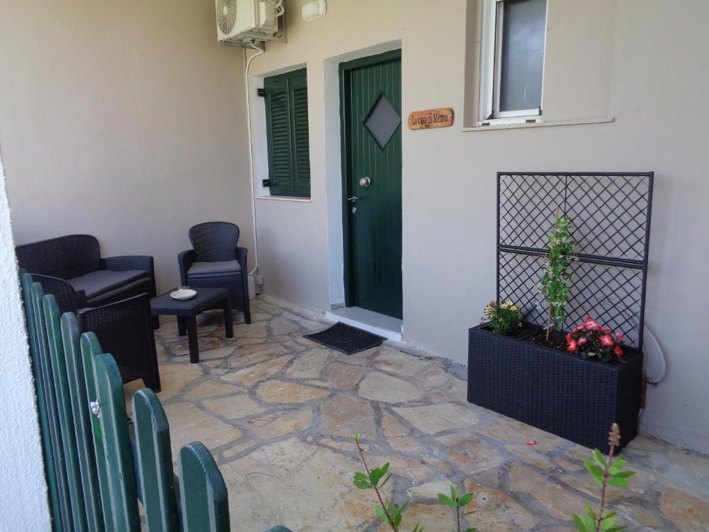 羅達的住宿－La casa di mezzo，一间设有绿门、椅子和门廊的房间