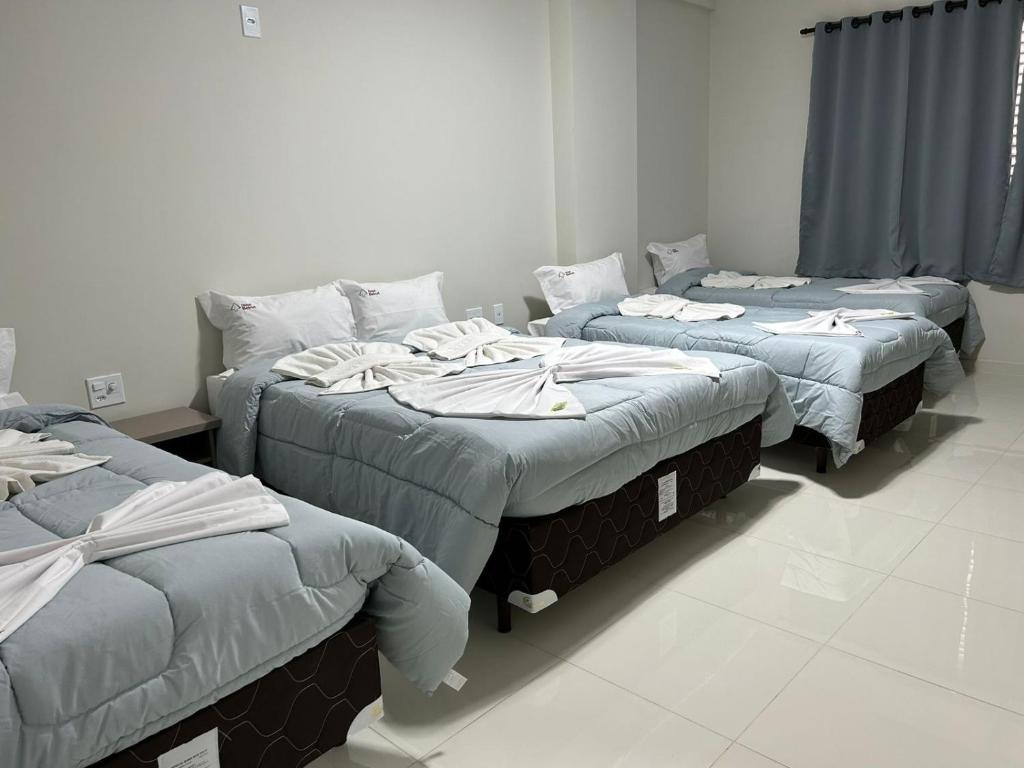ein Zimmer mit 3 Betten und Handtüchern darauf in der Unterkunft Hotel Beirut in Aparecida