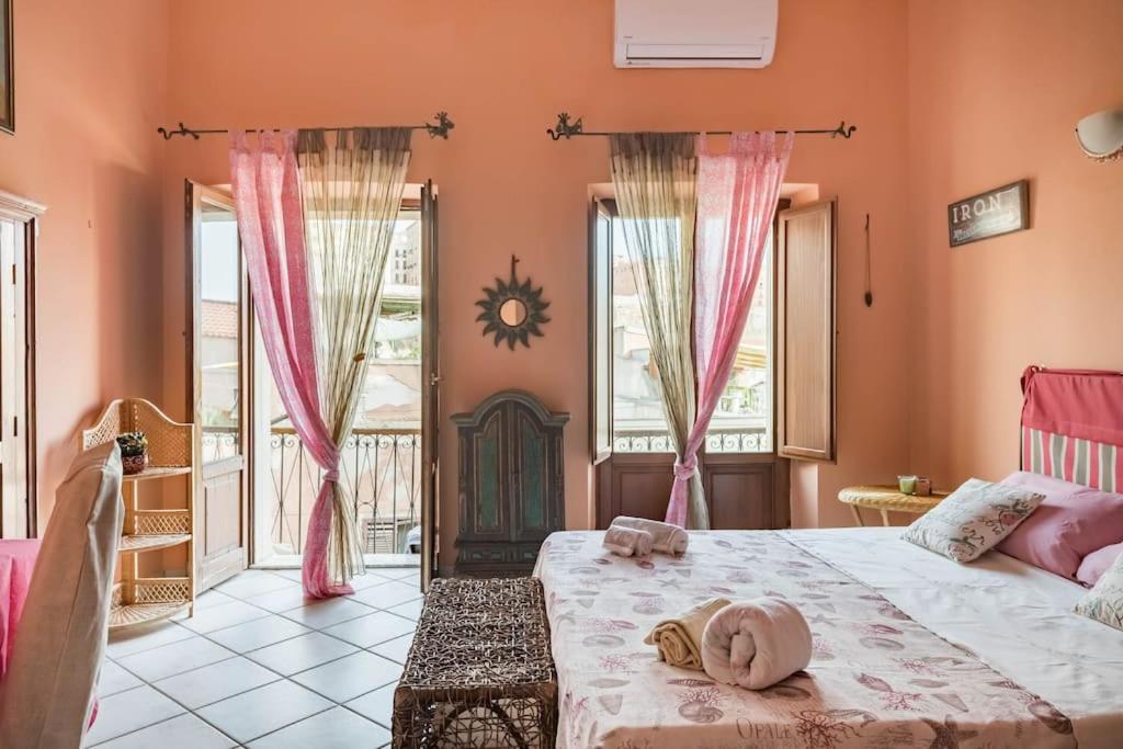 sypialnia z łóżkiem z różowymi ścianami i oknami w obiekcie LariBiancos Cagliari CENTRO STORICO w Cagliari