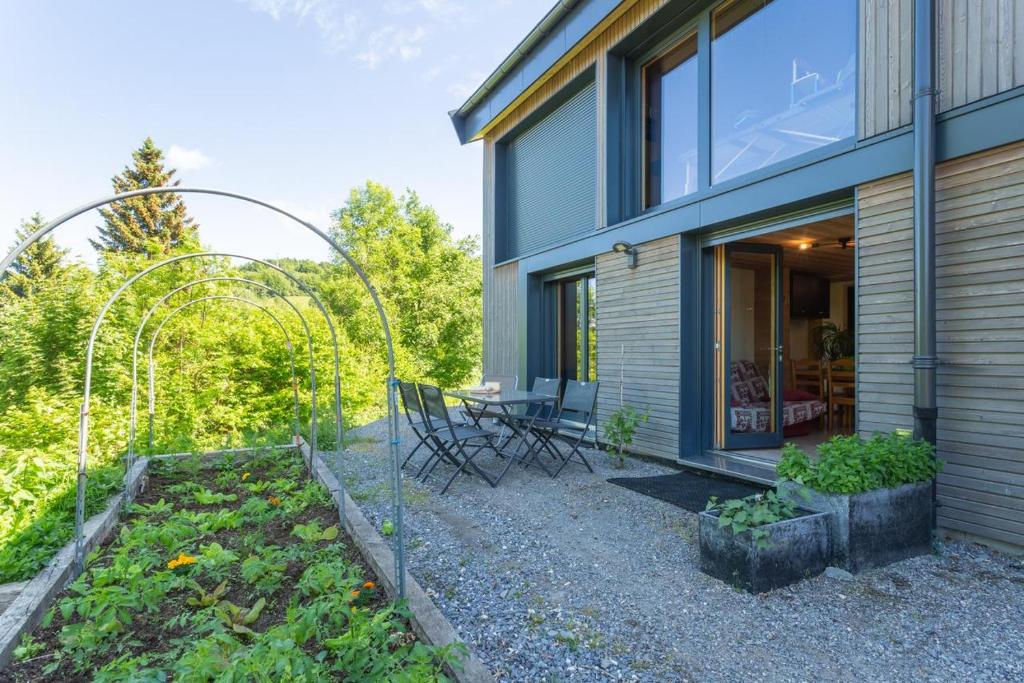 un jardín frente a una casa con mesa y sillas en Eco-gite Dans Chalet Neuf Au Pied, en Habère-Poche