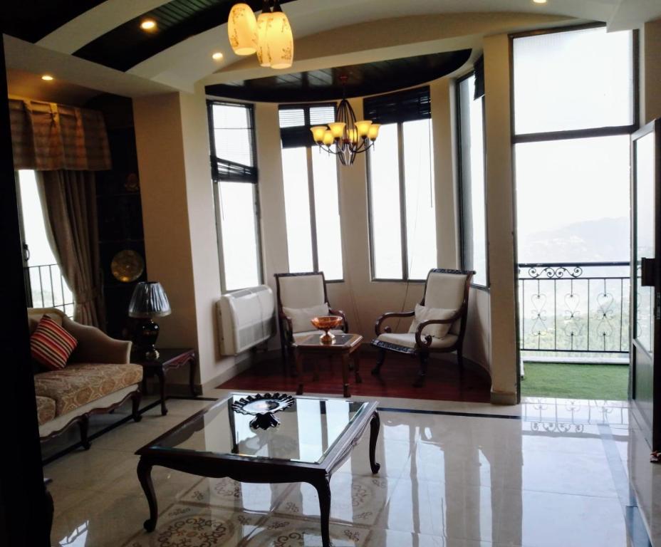a living room with a couch and chairs and windows at Noor Villa in Khaira Gali